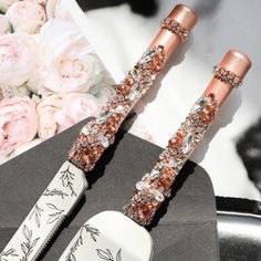 two rose gold and silver colored knifes next to flowers