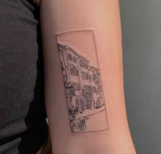 a woman's arm with a small black and white cityscape tattoo on it