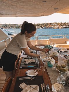 a woman setting a table on a boat