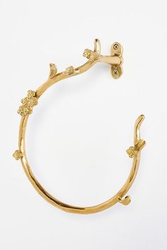 a gold bracelet with flowers and leaves on the outside, set against a white background