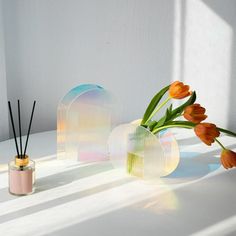 two vases with flowers in them sitting next to each other on a white table