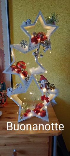 a christmas tree made out of ornaments on a wooden table with a yellow wall in the background