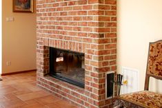 a brick fireplace in a living room next to a chair