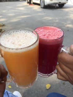 two people holding up glasses with drinks in them