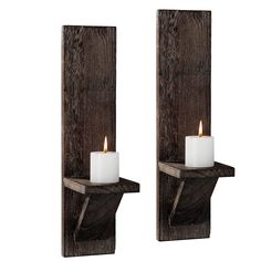 two candles are lit on the wooden wall sconces