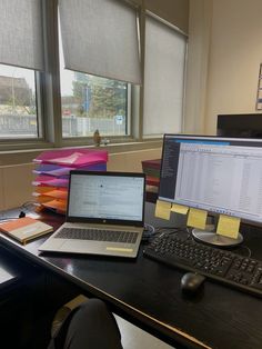 two laptops and a desktop computer sitting on top of a desk in an office