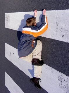 a young boy sitting on the side of a road with his hands in the air