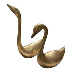 two brass swan figurines sitting next to each other on a white background,