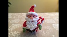 a crocheted santa clause figurine sitting on top of a tablecloth