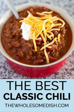 chili with cheese and sour cream in a red bowl on a counter top, text reads the best classic chili