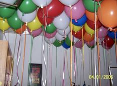 many balloons are hanging from the ceiling with streamers