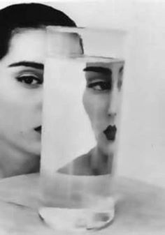 a woman is looking at her reflection in a mirror with the image of an individual's face on it