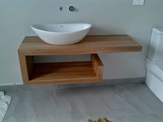 a white bowl sitting on top of a wooden shelf next to a toilet and sink