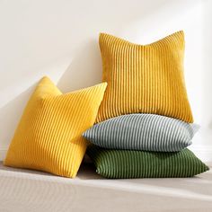 three pillows stacked on top of each other next to a wall with a white background