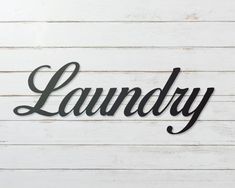 the word laundry written in black metal on a white wooden planks background with copy space