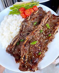 a white plate topped with meat, rice and veggies next to green beans