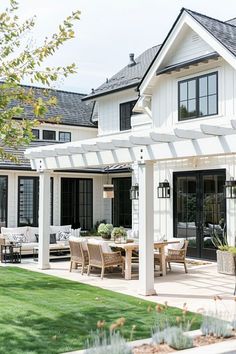 an outdoor dining area in front of a white house