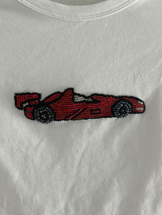 a white t - shirt with a red race car embroidered on it