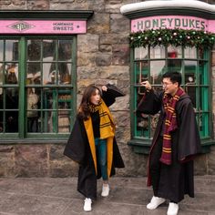 a man and woman dressed in harry potter costumes standing next to each other with their hands together