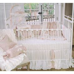 a white crib with pink bedding and pillows