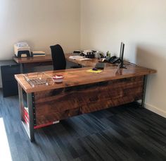 two desks in an office with wood flooring and black chairs on each side