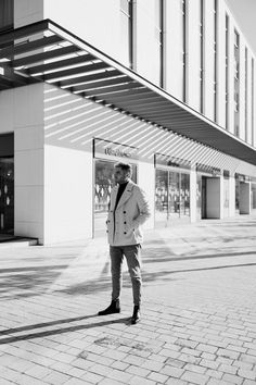 black and white photograph of a man standing in front of a building talking on his cell phone