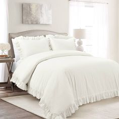 a white bed with ruffled sheets and pillows