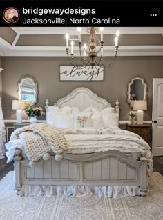 a large white bed sitting in a bedroom next to a chandelier and window