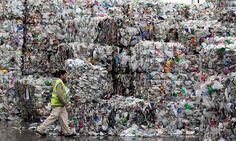 a man walking past a large pile of plastic bottles