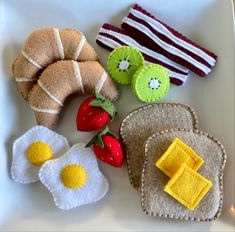 an assortment of felt food on a plate with strawberries, eggs, and toast