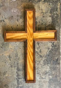 a wooden cross sitting on top of a cement wall