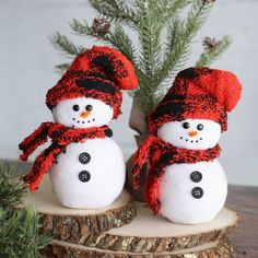 two snowmen sitting on top of a tree stump