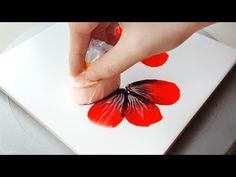 someone is painting a red flower on a piece of paper with acrylic paint