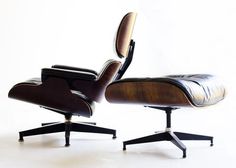 an eames lounge chair and ottoman in black leather with wood grained backrests