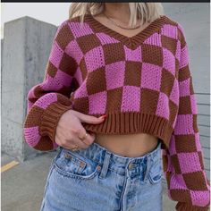 a woman with blonde hair wearing a pink and brown checkered knitted crop top