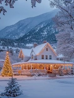 a large white house with christmas lights on it's roof and trees in the foreground