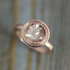 a pink diamond ring sitting on top of a wooden table