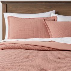 a bed with pink sheets and pillows on it