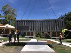 some people are doing something on top of a shipping container that is being lifted by a crane