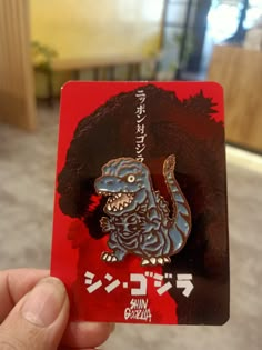 a person holding up a red and black card with an image of a dragon on it