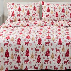 a bed with red and gold christmas trees on the sheets, pillows and pillow cases