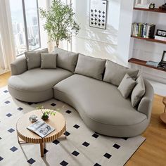 a living room with a large sectional couch and coffee table on the floor in front of a window