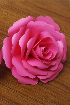 two pink flowers sitting on top of a wooden table