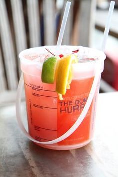 a drink in a plastic cup with two straws and a lime slice on top