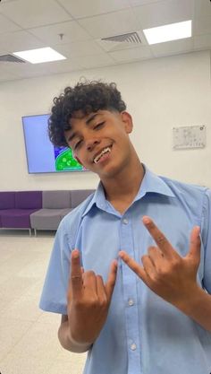 a young man making the v sign with his hands in front of him and smiling at the camera