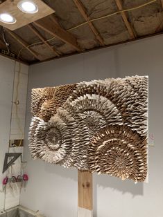 a sculpture made out of folded books on a wooden stand in front of a white wall