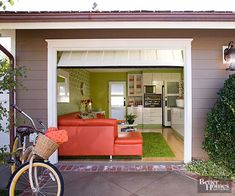 a bicycle parked in front of a garage with an orange couch on the door way