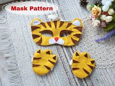 two masks made to look like tigers on a table with flowers in the back ground