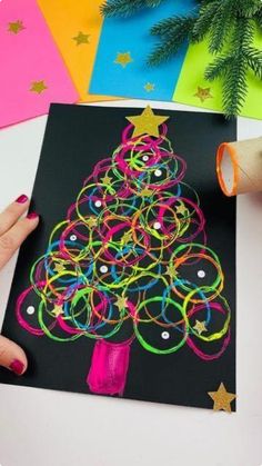 someone is making a christmas tree card out of colored construction paper and string art supplies