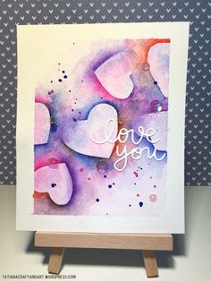 a card with the words love you written on it and hearts painted in watercolor